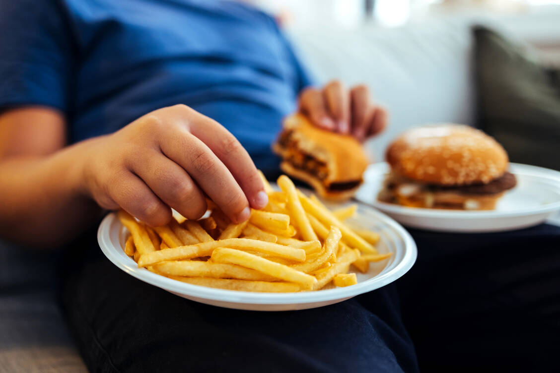 Gerade in stressigen Zeiten kann das späte Essen scheinbar Entspannung verschaffen. Dabei schadet es eher. / © Getty Images/ljubaphoto