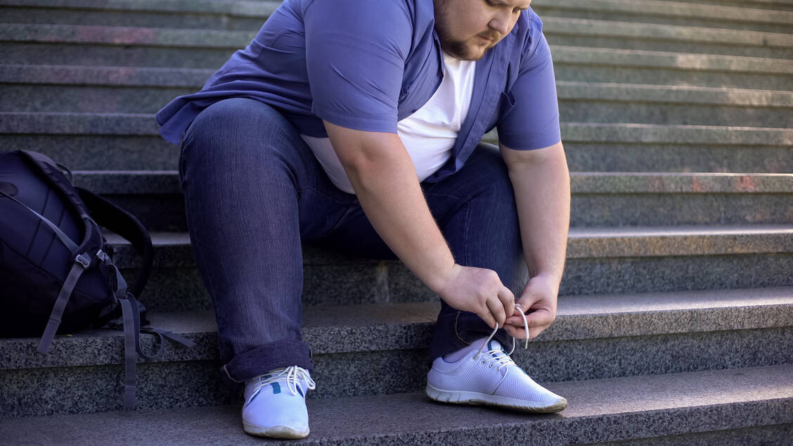 Übergewicht kann Menschen im alltäglichen Leben belasten, auch bei einfachen Tätigkeiten wie Schuhe binden. / Foto: Adobe Stock/motortion