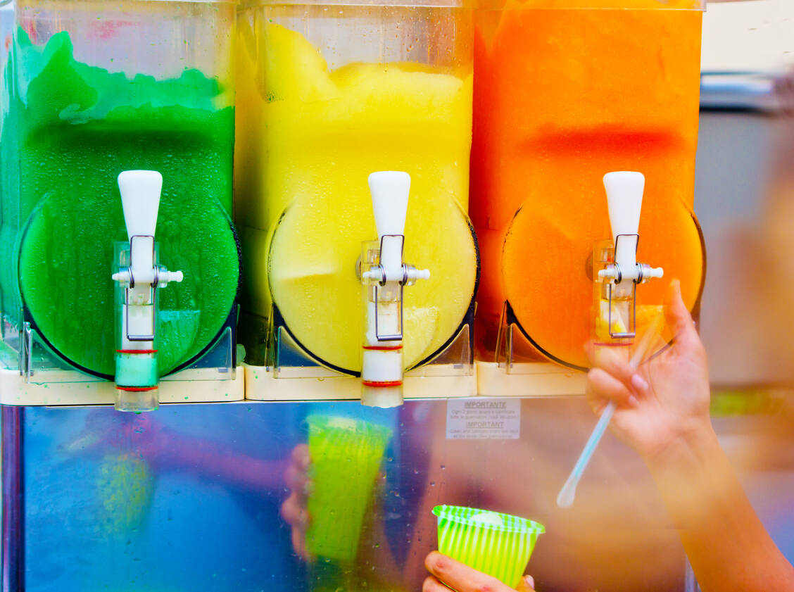 Slush Ice besteht aus zerkleinertem Eis, das mit aromatisiertem Sirup gemischt wird. Es wird etwa in Freizeitparks, auf Jahrmärkten oder im Kino verkauft und ist besonders bei Kindern beliebt. / © Getty Images/pmmart