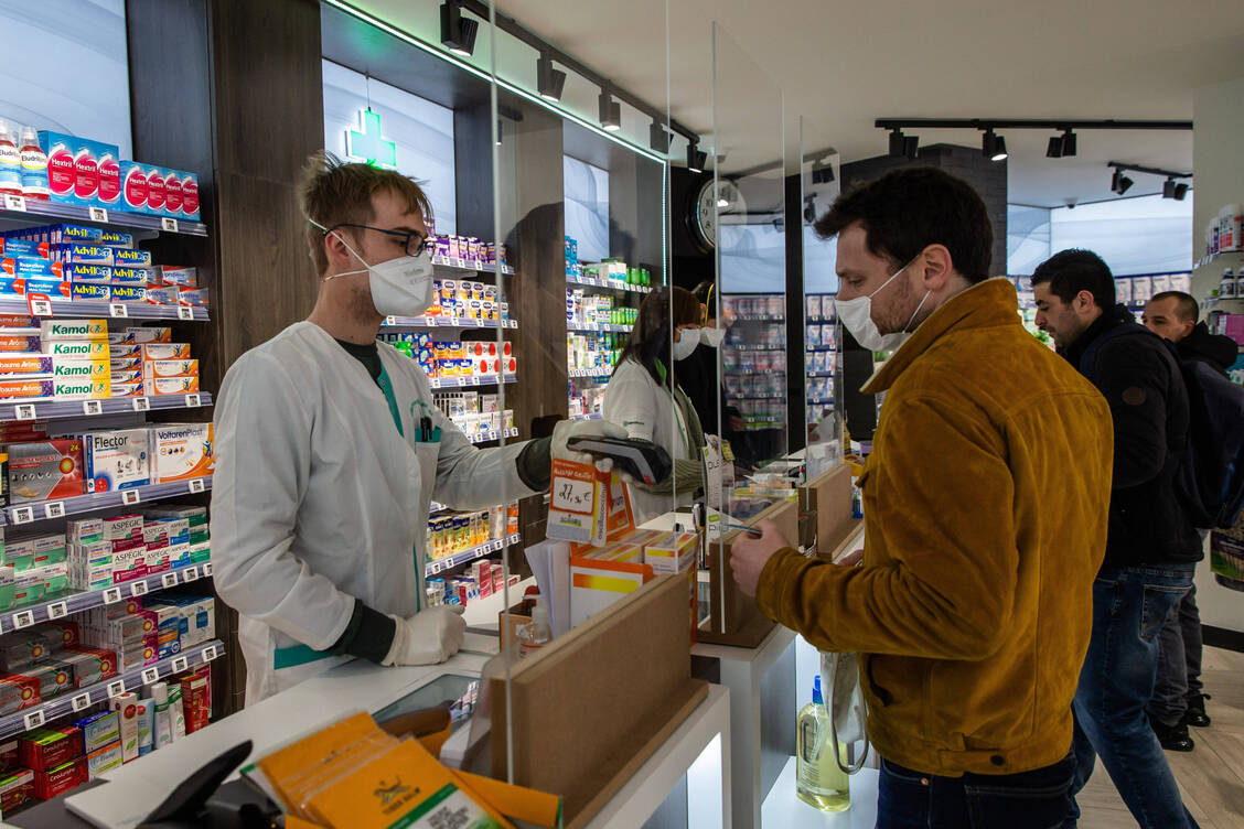 Viele Apotheker tragen auch hinter dem Spuckschutz eine Maske.  / Foto: Imago/Xinhua