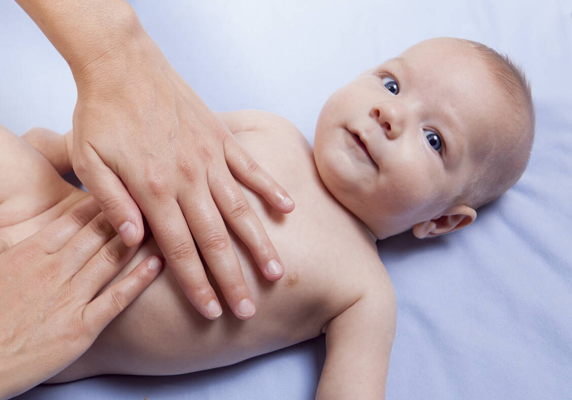 Mit warmen Händen Babys Bäuchlein massieren, lindert die Pein, die Blähungen bereiten. / Foto: Shutterstock/Juan Aunion