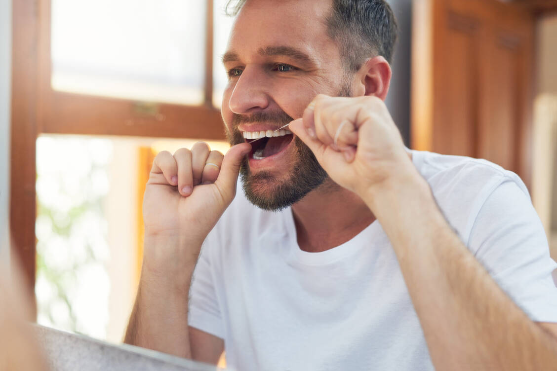 Karies kann auch unter Zahnkronen entstehen. Um das zu vermeiden, sollten möglichst täglich auch die Zahnzwischenräume gereinigt werden – zum Beispiel mit Zahnseide oder Interdentalbürstchen. / © Adobe Stock/Hira/peopleimages.com