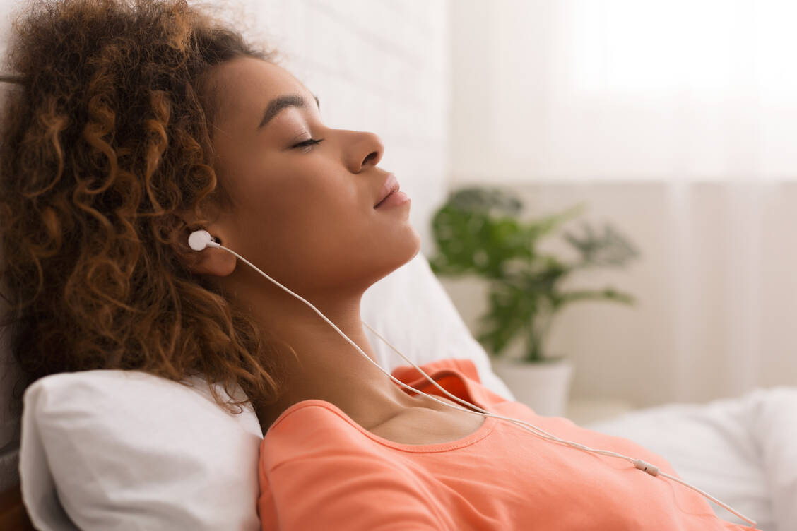 Sich feste Rituale zu schaffen, kann helfen, Stress abzubauen – zum Beispiel vor dem Schlafengehen keine Nachrichten mehr konsumieren, sondern Musikhören. / Foto: Getty Images/Prostock-studio