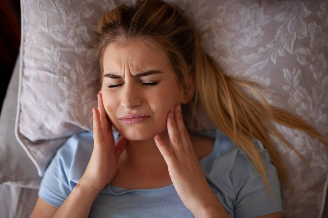 Morgendliche Verspannungen im Bereich des Kiefers oder sogar Kopfschmerzen können auf nächtliches Zähneknirschen hindeuten.  / Foto: Getty Images/Hope Connolly