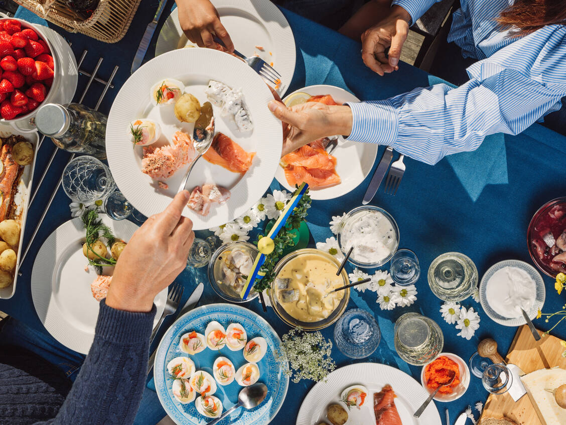 Fisch spielt in der nordischen Ernährung – wie hier beim Midsommar-Festessen – traditionell eine große Rolle. / © Getty Images/knape