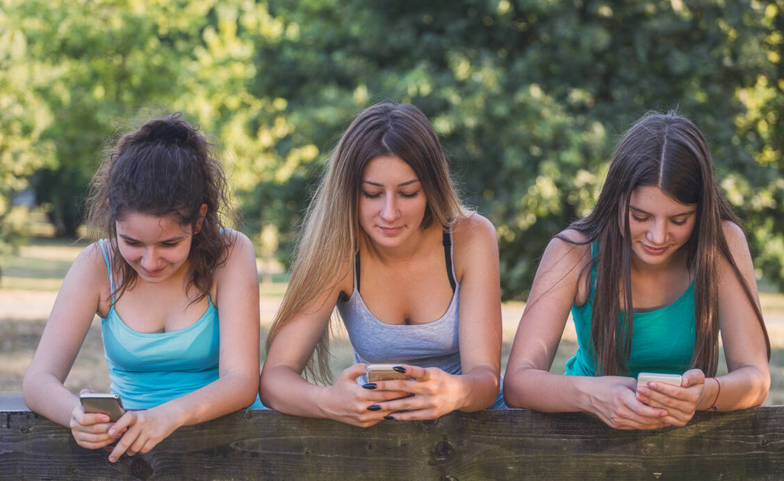 Den Kopf ständig über das Handy gebeugt – das kann zu fiesen Verspannungen führen. Dem kann man vorbeugen.  / © Getty Images/kajakiki