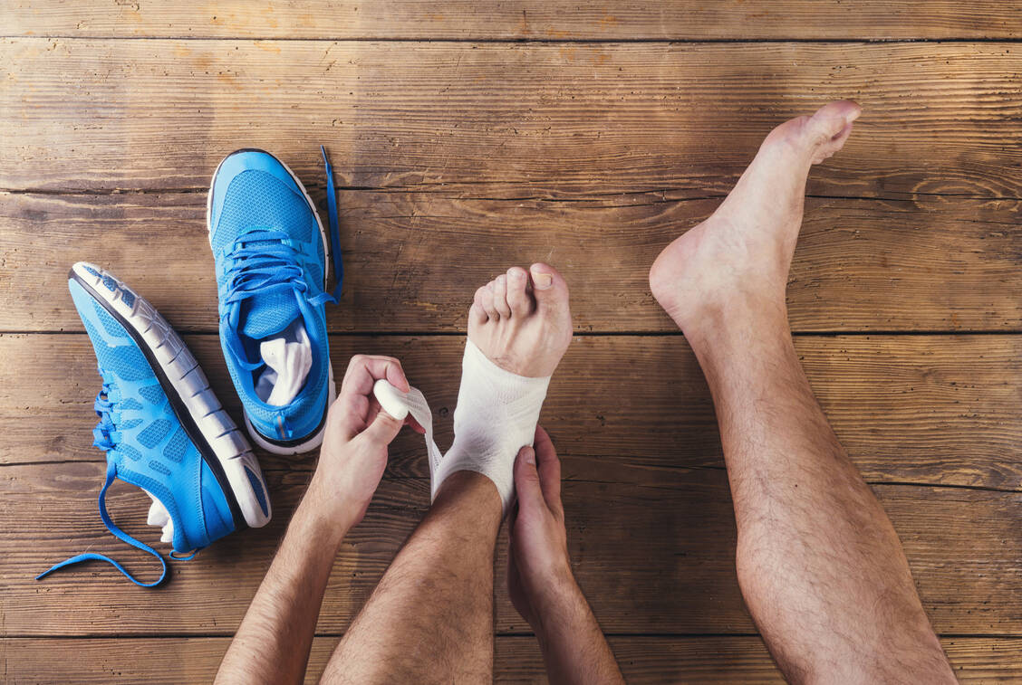 Ein fester Verband verhindert bei Sportverletzungen, dass sich Schwellung und Blutung ausbreiten / Foto: Adobe Stock/Halfpoint