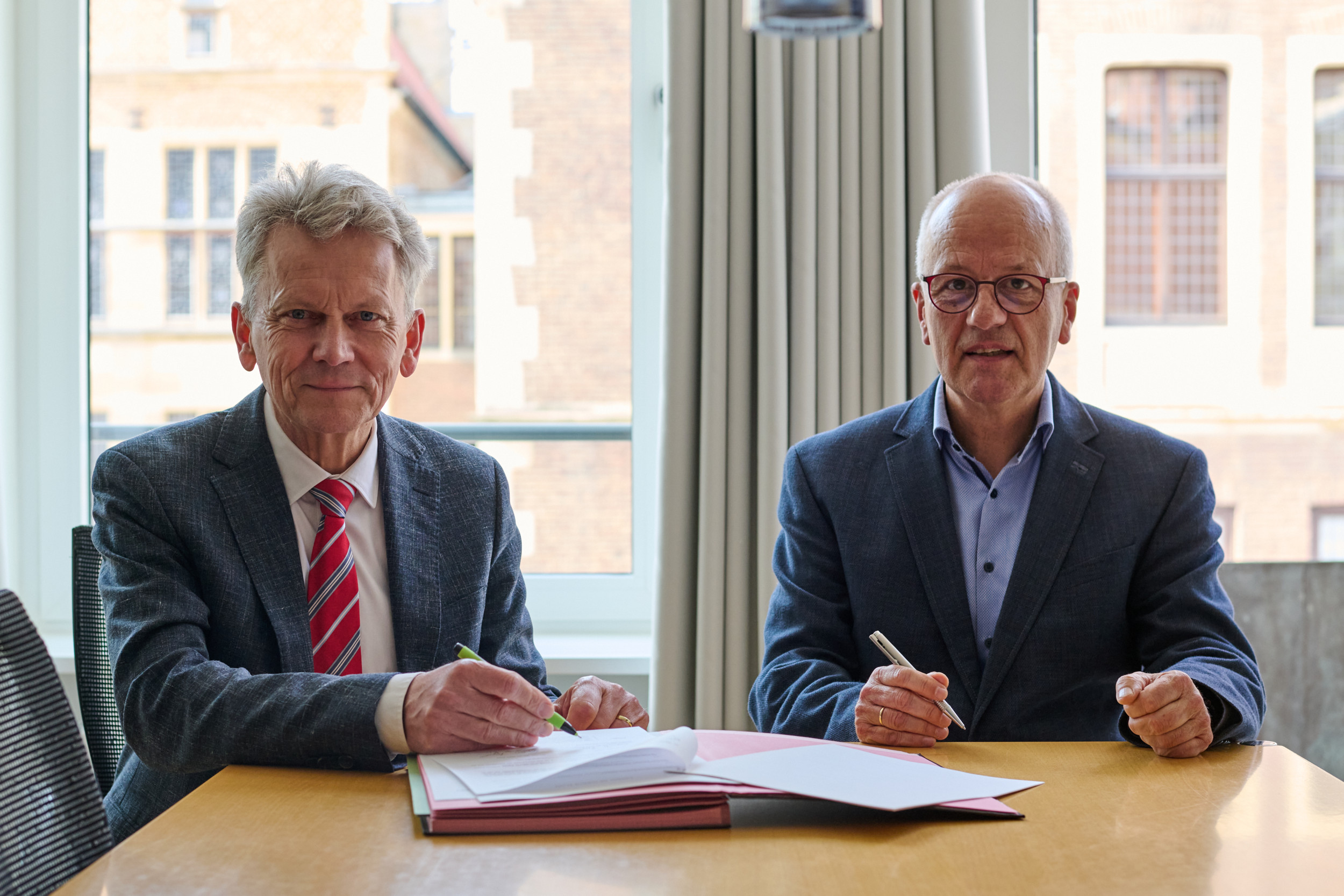 Stadtdirektor Thomas Paal (l.) und Andreas Vogd, Vorsitzender des Vereins PTA-Fachschule Westfalen-Lippe, unterzeichnen den Vertrag, mit dem die bisher städtische Berufsfachschule für PTA einen neuen Träger bekommt. / Foto: Stadt Münster/Phillina Zuther